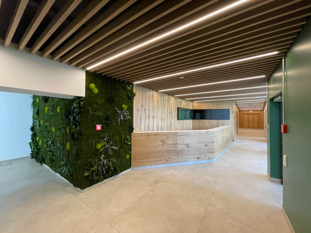 Empfang in modernem Bürogebäude. Mit individueller Holztheke und begrünter Wand.